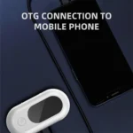 Mobile phone connected to white device via OTG cable on dark blue surface.
